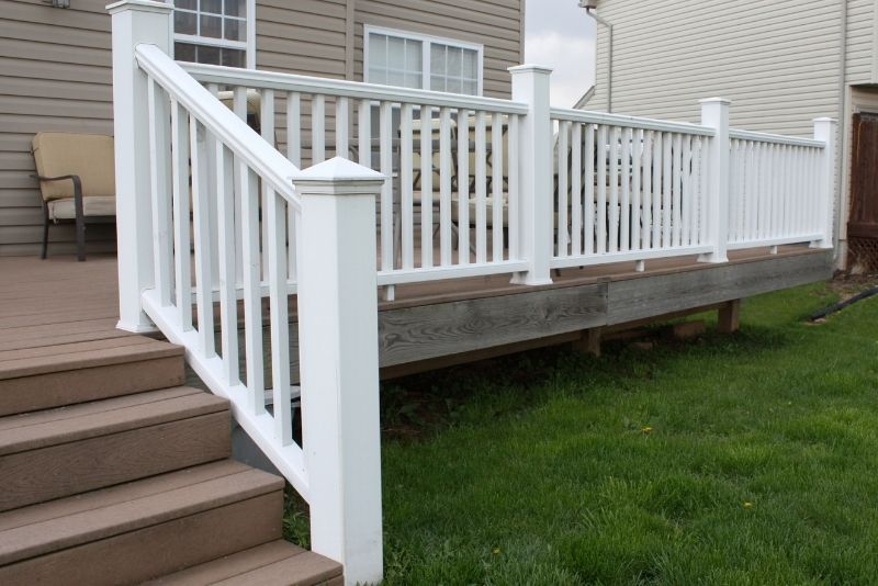 Raised timber deck with white balustrade railing and steps leading to the lawn